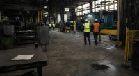 Fabriksgolv med stillastående maskiner och arbetare i bakgrunden